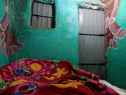 View from a bed covered with colorful cloth onto a colorful wall and ceiling, simple accommodation