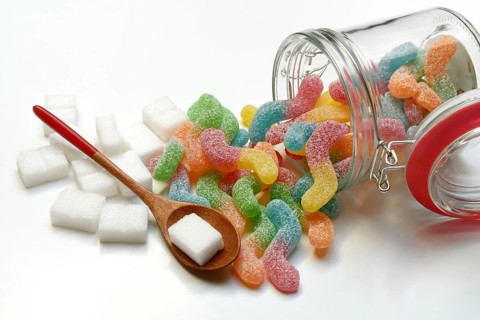 Lots of colorful jelly sweets in glass containers and sugar cubes, sugar consumption