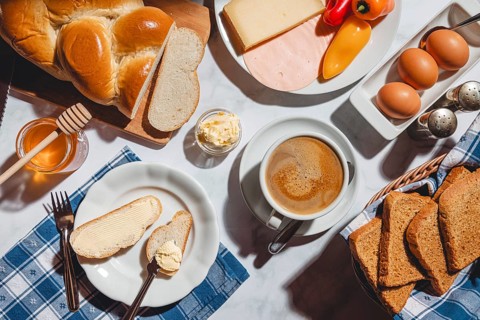 Breakfast with toast, sliced stollen, honey, cheese, ham, coffee, butter, bell pepper and eggs