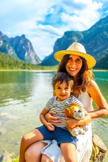 Happy mother and son are enjoying their summer vacation at lake dobbiaco with stunning mountain