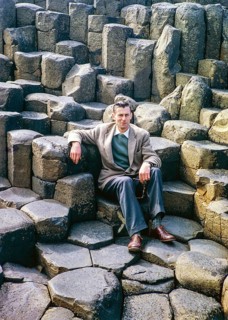Man sitting on basalt columns at the Giant's Causeway, County Antrim, Northern Ireland, United