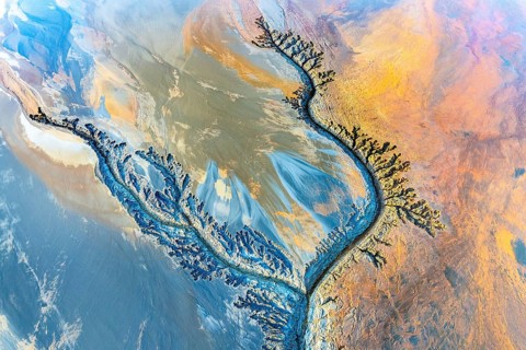 Aerial view of vibrant mud flats showcasing intricate fractal patterns with swirling textures and