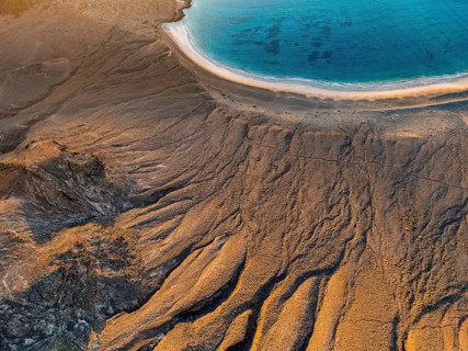 Cliff and beach with blue sea in evening light, top-down shot, near Mirador del Porrito, aerial