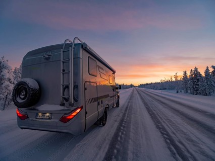 Motorhome on snowy road at sunset in winter, Lapland, Finland
