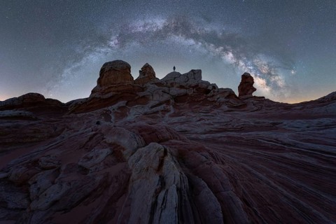 Unrecognizable person silhouetted against the Milky Way galaxy sprawling over the Utah desert's