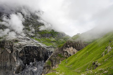 Dramatic mountain landscape covered in clouds with Berghaus Bäregg mountain hut, Bernese Alps,