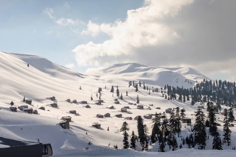 A stunning winter landscape in Georgia featuring snow-covered mountains dotted with quaint wooden