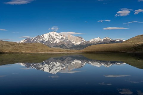 Granite towers of the Paine massif with snow-capped peaks are reflected in the Amarga lagoon, in