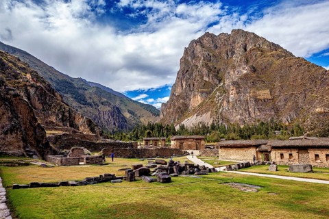 Grass-covered area in front of ancient ruins and a large mountain under clouds, The Inca ruins of