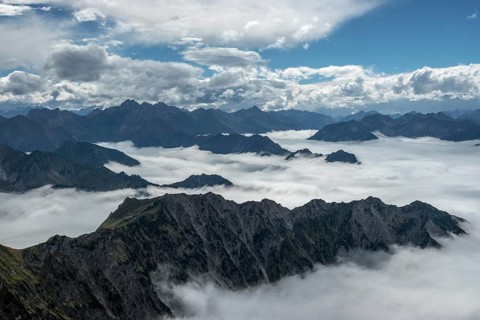 View from the Nebelhorn summit to mountains of the Allgäu Alps, mountains rising from fog in the