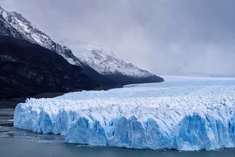 Perito Moreno glacier with shimmering blue ice break edge in Lake Argentino, snow-capped mountains