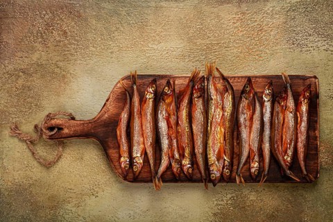 Cold smoked capelin, on a wooden chopping board, no people