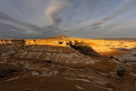 Eroded sedimentary rock formations with layered rock structures in evening light, mountain and