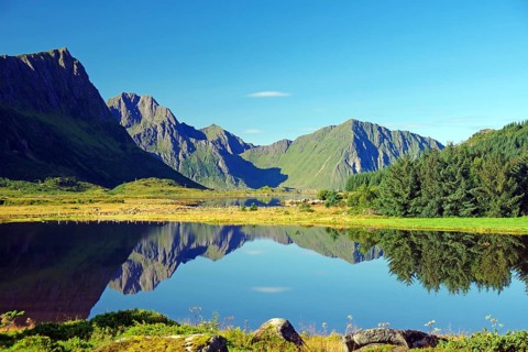 Mountains are reflected in a calm lake under a cloudless sky, Leknes, Vestvågøya, Lofoten,