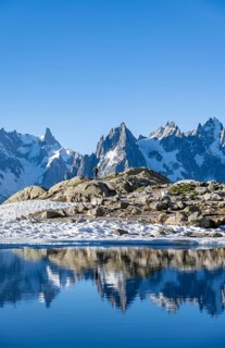 Young man in front of impressive mountain landscape in morning light, reflection in the Lac Blanc