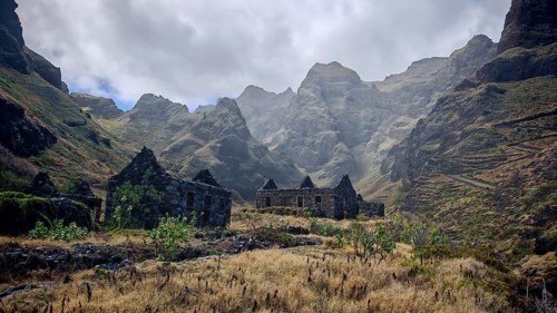 Stone ruins of old houses made of volcanic stone against a spectacular mountain backdrop with thick