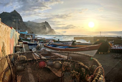Coastal view with nets, baskets and fishing boats at sunset, wall with graffiti, romantic harbor