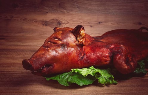 Baked, fried piglet, on a wooden table, no people, The whole piglet is baked and served on the