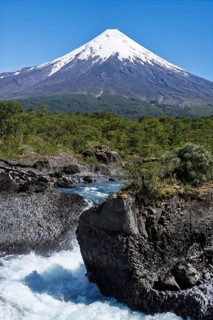 Snow-covered Osorno volcano with offshore Saltos del Petrohué, waterfalls over basalt rocks, dense