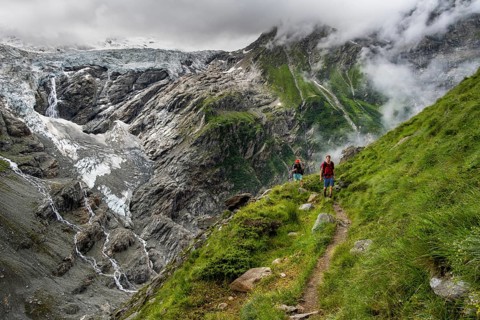 Two mountaineers on a hiking trail, cloudy mountain landscape with Grindelwald-Fiescherfirn