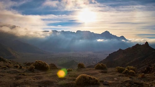 Dramatic mountain landscape with brilliant light through cloud cover and green vegetation, Teide,