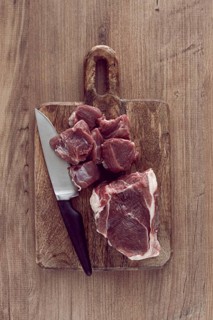 Raw beef meat, sliced on a cutting board, with a knife, no spices, no herbs, top view, wooden