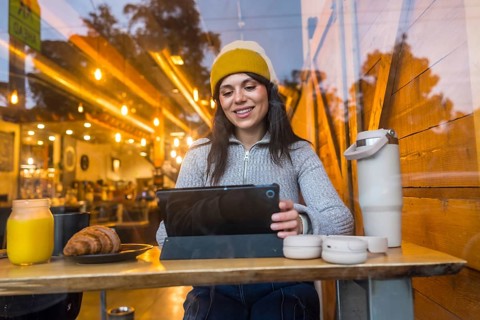 Smiling woman sitting at a table in a bustling san francisco coffee shop, happily interacting with
