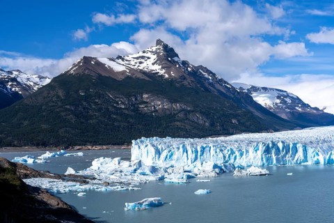 Perito Moreno glacier with shimmering blue ice front and chunks of ice in Lake Argentino, behind it