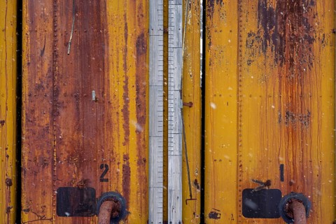 Rusted yellow tanks with numbering and level measurement bar, detailed view in case of snowfall,