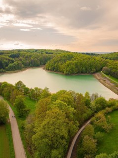 Idyllic lake with surrounding forest and winding paths under a cloudy sky, Glems reservoir, Swabian