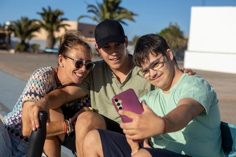 A joyful family moment as a teenager with Down Syndrome takes a selfie with loved ones The sunny