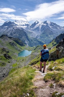 Hiker on hiking trail, mountain lake Lac de Louvie with glaciated summit of the Grand Combin, Val