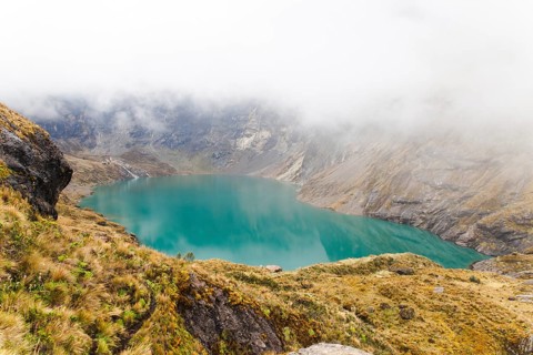 A stunning turquoise crater lake nestled within the rugged mountains of El Altar volcano, Ecuador,