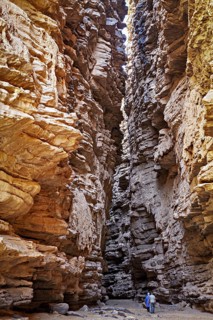 Deep, narrow gorge with dramatic incidence of light and a person surrounded by rocky walls, rocky