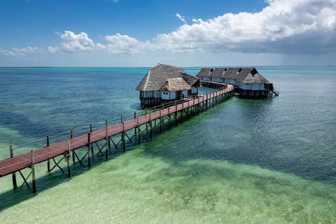 Luxury overwater wooden boardwalk and traditional thatched bungalows spanning across the crystal