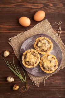 Tartlets with meat and cheese on brown wooden background and linen textile. top view, flat lay,