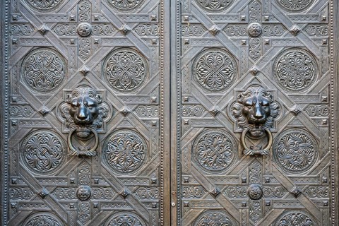 Artfully decorated bronze doors with lion heads as door pullers or door knockers on the Gallus