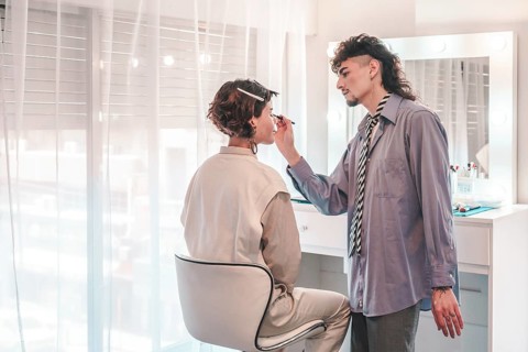 Professional makeup artist carefully applying eyeliner to a model's eye, enhancing her beauty in a