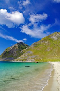 A secluded sandy beach meets turquoise blue sea under picturesque hills and sky, Haukland, Leknes,