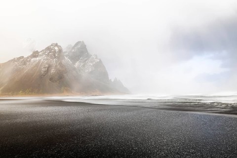 Sleet on black lava sandy beach against mountain backdrop, sea, winter, Stokksnes, Vestrahorn,