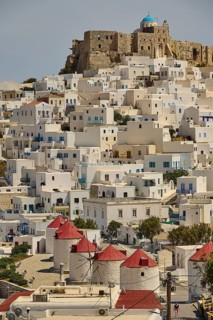 Windmills and white houses on a slope below a stone fortress on a hill, Querini Castle, Chora,