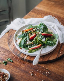A vibrant and nutritious spinach salad topped with crisp apple slices, scattered pecans, and