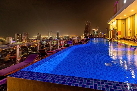 Nighttime city view with illuminated pool, modern buildings and relaxed atmosphere, infinity pool