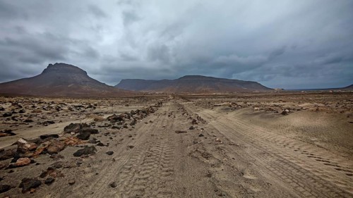 Desert road leads through rugged surroundings to distant mountains, hiking Calhau, Baia das Gatas,