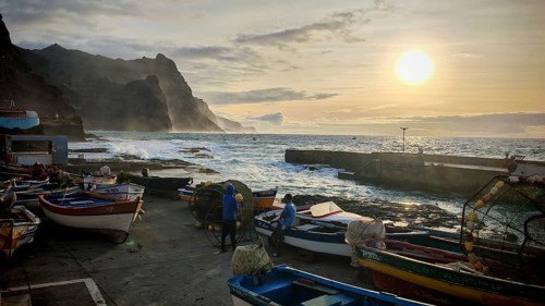 Coastal landscape with fishing boats and setting sun, waves hitting rocks, romantic light, Ponta do
