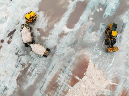 Excavator and lorry at a harvesting pan of the Walvis Bay Salt works. Aerial view. Drone shot.