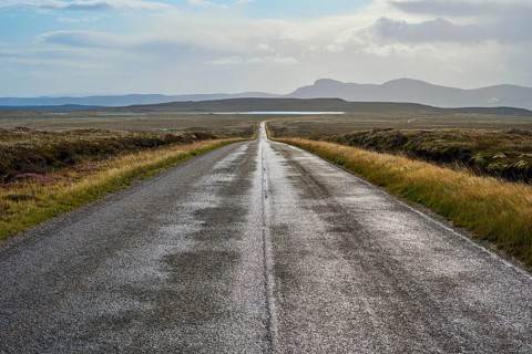 Endless road through vast countryside with distant mountains and dramatic skies, Tongue, Lairg,