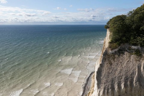 White chalk cliffs at Hundevængsfald with a view of the Baltic Sea towards Møn Lighthouse under a