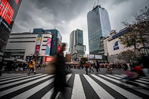 Crowd crossing zebra crossing on a large intersection, motion blur, back modern houses with