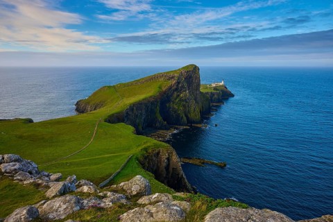A far-reaching view of a coastline with a lighthouse and green cliffs, Neist Point Lighthouse,